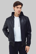Front studio shot of a man wearing a slim-fit black leather bomber jacket with a snap-tab collar and zippered pockets, styled with dark pants against a white background.