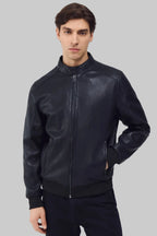 Front studio shot of a man wearing a slim-fit black leather bomber jacket with a snap-tab collar and zippered pockets, styled with dark pants against a white background.