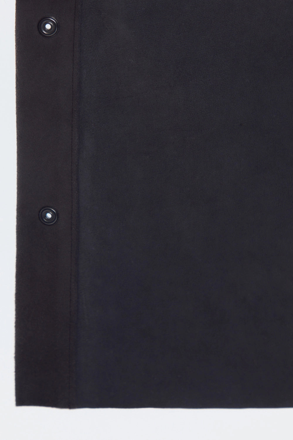 Front studio portrait of a man wearing a minimalist, charcoal gray suede shirt jacket snapped completely closed, featuring a clean concealed placket and point collar against a solid white background.